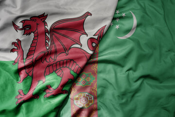 big waving national colorful flag of wales and national flag of turkmenistan .