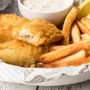 A close up of fresh homemade fish and chips served with tartar sauce.