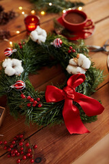 winter holidays, diy and hobby concept - close up of christmas fir wreath and decorations on wooden table