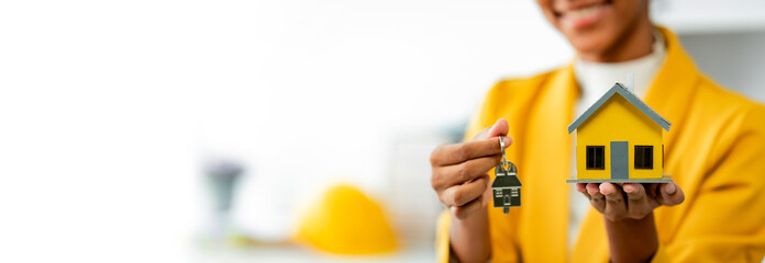 African American female real estate agent delivers house model to client mortgage loan contract Make a contract to buy and sell a house. and home insurance contract home mortgage loan concept