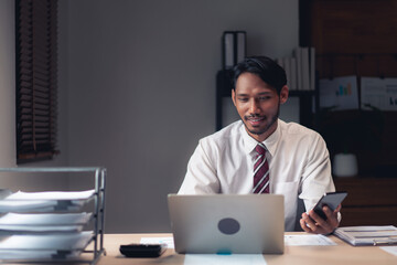 Businessman read report on laptop and checks data on smartphone while analysis financial of project