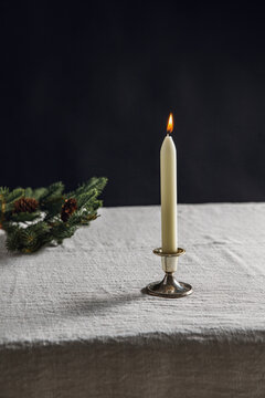 winter holidays and celebration concept - close up of candle burning on table and fir branch over black background