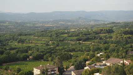 Stunning view of wineyards and farmlands with small villages on the horizon. Summer rural landscape of rolling hills, curved roads and cypresses of the Provence, France.