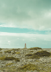 fotografia de um farol rodeado de pedras e vegetação no algarve 