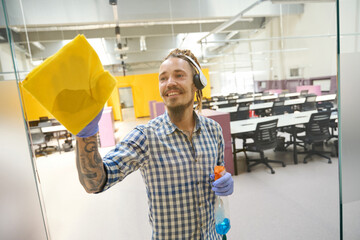 Man wearing headphones rubs the glass with a yellow cloth