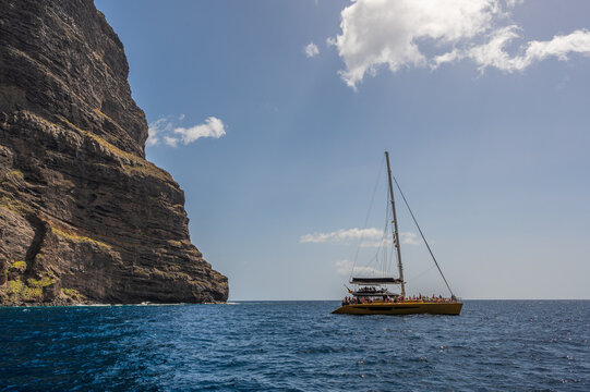 The cliffs of Los Gigantes, Tenerife, rising out of the sea, with a sailing boat on the ocean in front of them