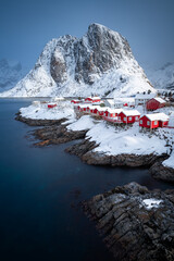 Vertical photo of Hamnoy fishing village in Norway. Lofoten winter scene with typical red houses and a snowy mountain in the background. - 648592040