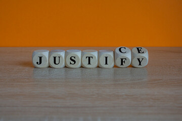 Turned wooden cubes and changes the word justify to justice. Beautiful wooden table, orange background. Copy space.