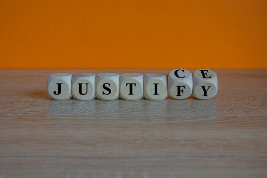 Turned wooden cubes and changes the word justify to justice. Beautiful wooden table, orange background. Copy space.
