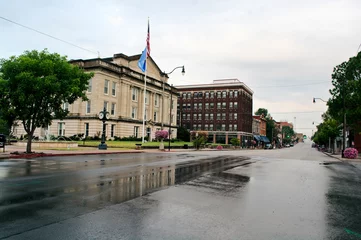 Fototapete Route 66 Looking west on Route 66 rainy morning Sapulpa, Oklahoma. Wet pavement of Dewey Avenue reflects the Creek County Courthouse. Small town USA.  © Richard