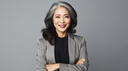 Asian female psychologist stands with her arms folded, looking at the camera against a gray background. Product advertisement portrait of a stylish grey-haired woman. generative ai