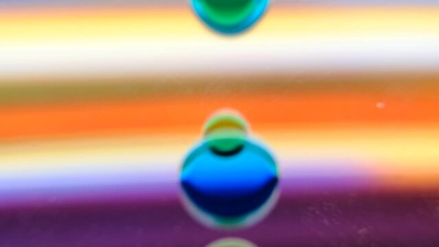 defocused of various sizes of transparent liquid bubbles floating down on colorful moving light horizontal lines background