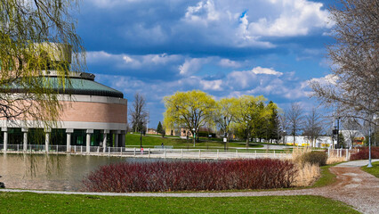 There is a pond, many red and green plants, and domed buildings in the park