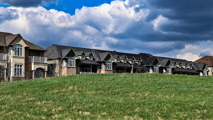 Rows of townhouses under dark clouds with patches of blue sky and white clouds