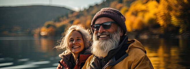 Happy active elderly couple is engaged in canoeing on the lake in the fall - obrazy, fototapety, plakaty