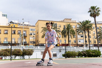 Portrait of a red haired and freckled girl doing inline skating in a city park, concept of...