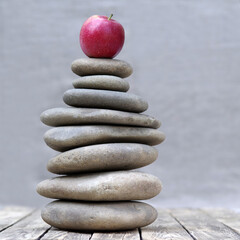 Red apple on a pebble pyramid. At the pinnacle of balance.