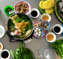 Colorful Table with Authentic Vietnamese Street Food - Fish Noddles Soup with Fresh Seafood, Vegetables, Fish and Meat Balls, Chillies and Sauces. Flaming Hot Pot. 