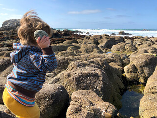 Having fun with  tide pools - Little boy exploring beach and the ocean: throwing rocks, playing in...