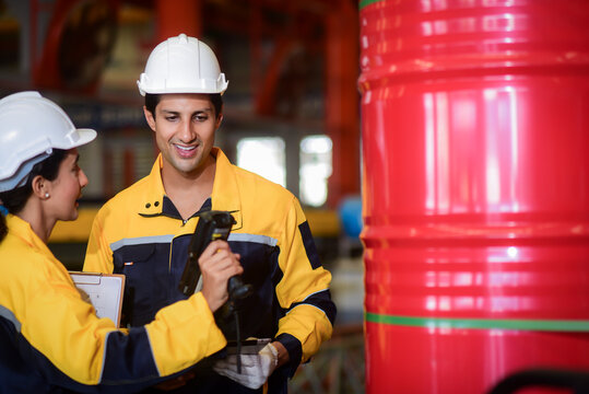 2 Latino male and female auditor wearing safety uniform workwear with handheld barcode scanner or integrated rfid handheld reader and tablet computer counts goods in warehouse of factory Manufacture.