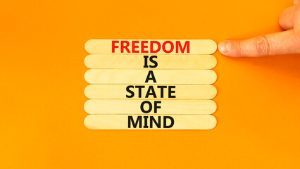 Freedom in mind symbol. Concept words Freedom is a state of mind on wooden sticks on a beautiful orange table orange background. Businessman hand. Business freedom is a state of mind concept.
