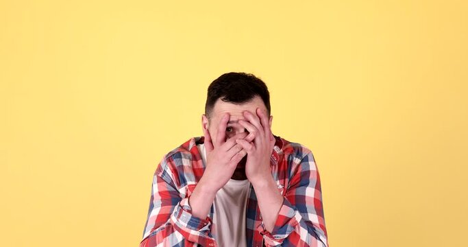 Playful Young  Man Hiding His Face With Palms, Playing Hide And Seek And Having Fun On Yellow Background