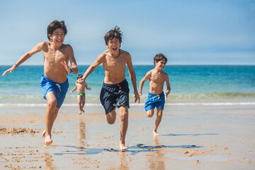 Brothers running on the beach on a sunny day.