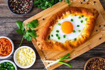 Georgian cuisine -  khachapuri cheese-filled bread with fried egg on wooden background
