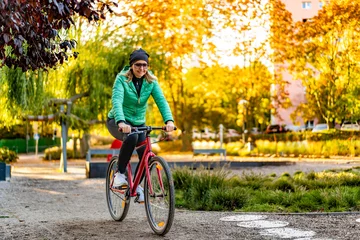 Tuinposter Woman riding bicycle in city park  © Jacek Chabraszewski