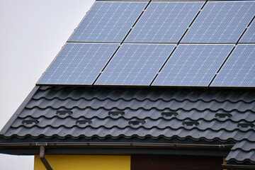 Naklejka premium Private home roof covered with solar photovoltaic panels for generating of clean ecological electric energy in suburban rural town area. Concept of autonomous house
