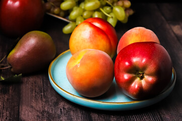 Red apple in a plate and other fruits on a rustic table. Shallow depth of field