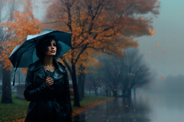 Woman with umbrella strolling in the rain in autumn park