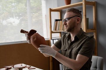Archeologist works in office, researching discovered ancient civilization cultural artifact