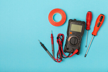 Electrician tools on blue background.Multimeter,construction tape,electrical tape,...