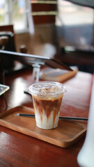 Closeup of Iced Caramel Macchiato at the coffee shop, Caramel Macchiato is a classic macchiato beverage. It consists of vanilla syrup, espresso, steamed milk, foam, and caramel drizzle