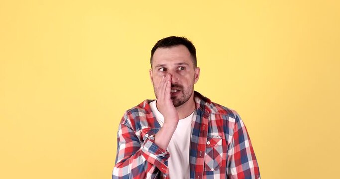Man doing eavesdropping gesture over yellow background. 