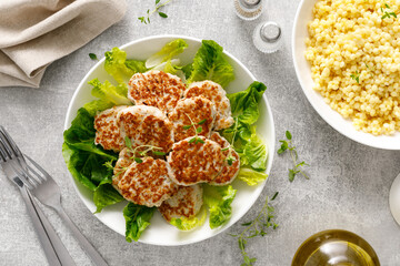 Chicken patties, cutlets with fresh romaine lettuce salad and couscous, top down view