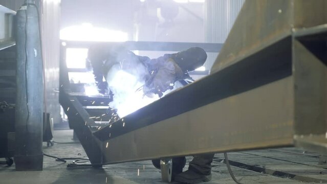 Two welders are welding an I-beam structure at the factory