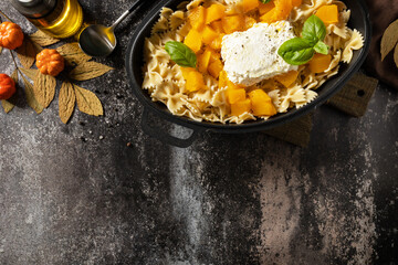 Fetapasta. Baked feta pasta, or Tiktok pasta. Feta pasta recipe made of pumpkins, feta cheese, garlic and herbs on dark stone background. View from above. Copy space.