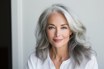 A picture of a woman with grey hair wearing a white shirt. This image can be used to depict elegance, maturity, or professionalism.
