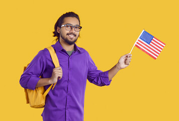 Portrait of young Indian man who is studying in USA. Happy exchange student in purple shirt and...