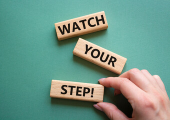 Watch your Step symbol. Concept words Watch your Step on wooden blocks. Businessman hand. Beautiful grey green background. Business and Watch your Step concept. Copy space.