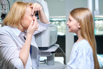Experienced female ophthalmologist teaching child how to use corrective lenses