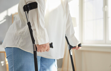 Cropped close up photo of a handicapped overweight fat woman trying to walk using her crutches in...