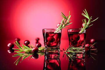 Cranberry liquor with rosemary on a red background.