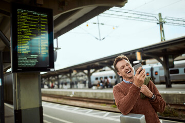 Middle aged businessman using a smartphone while waiting for his train at the train station