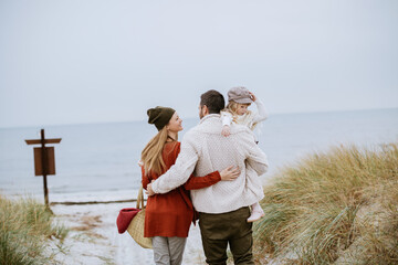 Happy young caucasian couple having fun and walking on a sandy beach during winter