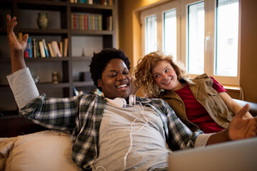 Young interracial couple using the laptop on the couch in the living room at home