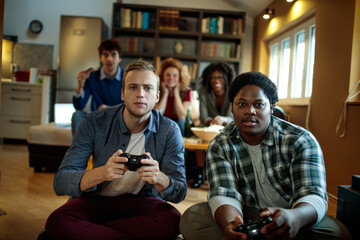 Young and diverse group of friends playing video games on a gaming console in the living room