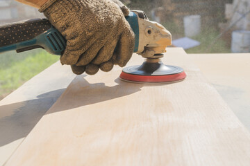 Grinding of an oak board with an angle grinder. A gloved hand. Wooden dust in the air.